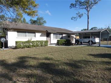 Charming single-story home with a carport and well-maintained landscaping on a sunny day at 55 Sw Fig Tree Ln, Dunnellon, FL 34431