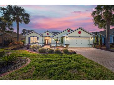 Charming single-story home featuring a well-manicured lawn, brick driveway, two-car garage, and a beautiful sunset sky at 8826 Sw 83Rd Cir, Ocala, FL 34481