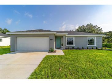 Charming single-story home with a well-manicured lawn, gray siding, and a two-car garage at 17094 Sw 39Th Cir, Ocala, FL 34473