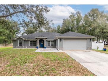 Charming single-story home with a well-manicured lawn, stone accents and a two-car garage at 2045 Marion County Rd, Weirsdale, FL 32195