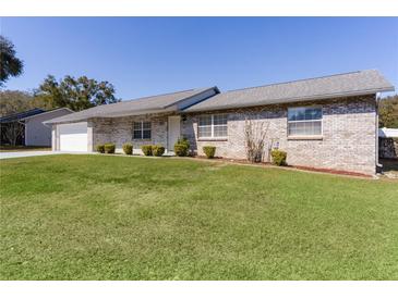 Charming single-story home featuring a well-manicured lawn and a classic brick exterior under a clear blue sky at 3853 Se 60Th St, Ocala, FL 34480