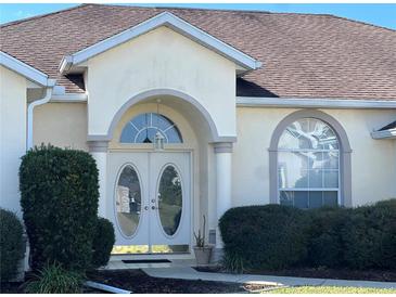 Elegant front entrance featuring a double door and arched window, flanked by well-maintained landscaping at 5500 Nw 23Rd Pl, Ocala, FL 34482