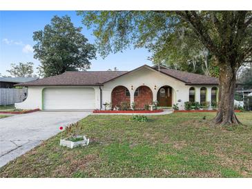Charming single-story home featuring unique brick accents, arched entryways, mature trees, and an attached two-car garage at 711 Se 26Th St, Ocala, FL 34471