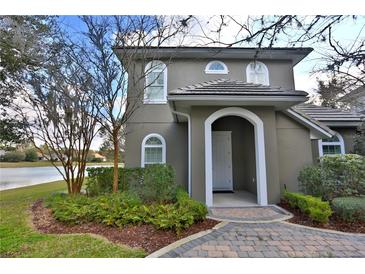 Charming two-story home featuring arched entryway, beautiful landscaping, and serene lake view at 8135 Nw 26Th Lane Rd, Ocala, FL 34482