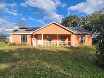 Cozy single-story home featuring a charming front porch, solar panels, and a well-maintained lawn at 13521 N Magnolia Ave, Citra, FL 32113