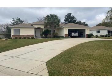 Charming single-story home features a light-yellow exterior, well-manicured lawn and attached garage at 13766 Se 89 Ave, Summerfield, FL 34491