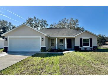 Charming single-story home with neutral paint, attached two-car garage, and manicured lawn at 13936 Sw 113 Ln, Dunnellon, FL 34432