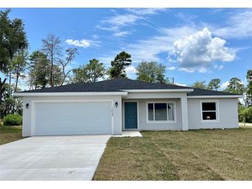 Charming single-story home featuring a two-car garage, a teal front door, and a well-manicured lawn at 269 Marion Oaks Golf Way, Ocala, FL 34473