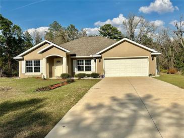 Charming single-story home featuring a two-car garage and a well-manicured lawn under a bright blue sky at 5765 Sw 164Th Pl, Ocala, FL 34473