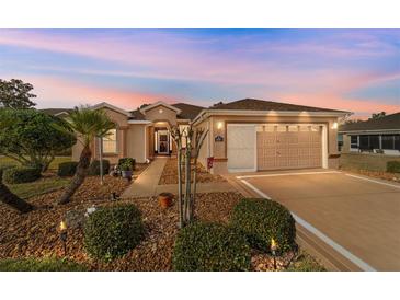 Charming single-story home featuring a well-manicured lawn and two-car garage at dusk at 1029 Sw 157Th Ln, Ocala, FL 34473