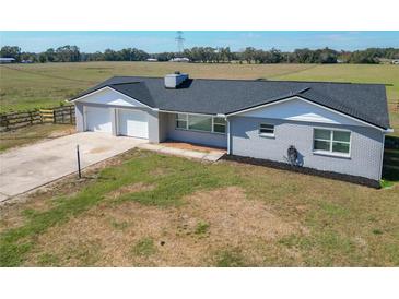 Charming single-story home featuring a gray brick exterior, black roof, and attached two-car garage at 13800 Se 80Th Ave, Summerfield, FL 34491