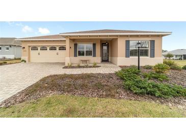 Charming single-story home featuring a brick driveway, attached garage, and covered porch with decorative shutters at 9399 Sw 106Th Ave, Ocala, FL 34481