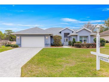 Charming single-story home with a well-manicured lawn, gray paint, and an attached two-car garage at 11593 Sw 75Th Cir, Ocala, FL 34476