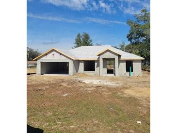 New home construction with attached garage and modern design elements under a bright, clear sky at 20079 Sw 84 St, Dunnellon, FL 34431