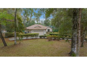 Charming single-story home featuring a well-manicured lawn and mature trees surrounding the property at 7810 Sw 186Th Cir, Dunnellon, FL 34432