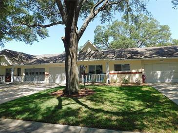 Charming one-story villa with an attached garage, a well-manicured lawn, and a large shade tree in the front yard at 9652 Sw 84Th Ter # C, Ocala, FL 34481