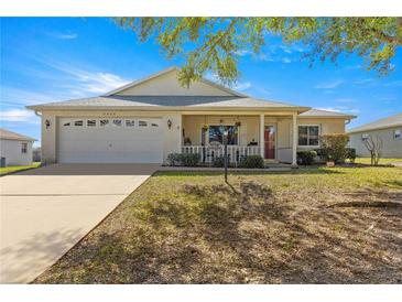 Charming single-story home featuring a cozy front porch and a well-maintained, lush green lawn with a white brick facade at 9866 Sw 97Th Ln, Ocala, FL 34481