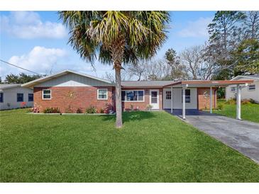 Charming brick home featuring a well-manicured lawn and a convenient carport at 21615 Sw Raintree St, Dunnellon, FL 34431