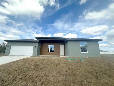 Modern one-story home featuring a gray facade, wood toned accents, and a two-car garage at 4501 Sw 110Th Ln, Ocala, FL 34476