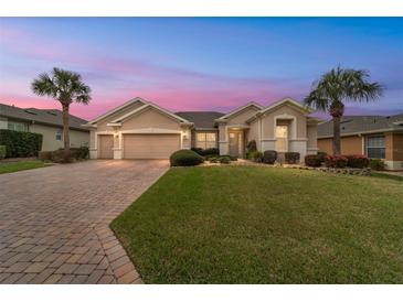 Inviting single-Gathering home with a well-manicured lawn, paver driveway and two-car garage, complemented by palm trees at 9863 Sw 63Rd Loop, Ocala, FL 34481