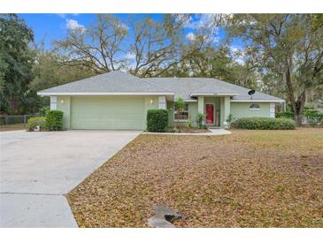 Charming single-story home with a well-manicured front lawn and a welcoming red front door at 16320 Se 16Th Pl, Ocklawaha, FL 32179