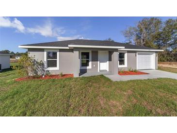 Charming single-story home with gray stucco exterior, manicured lawn, and attached garage at 2275 Sw 146Th Ct, Ocala, FL 34481