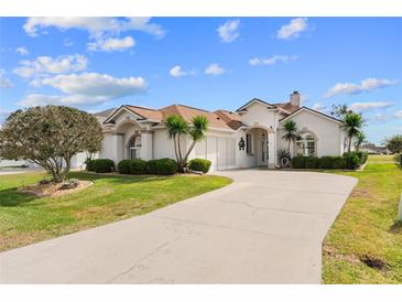 Charming stucco home with a well-manicured lawn and a long driveway at 2399 Nw 53Rd Avenue Rd, Ocala, FL 34482