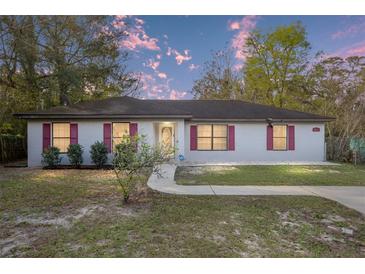 Charming single-story home featuring red shutters, a well-manicured lawn, and a paved walkway at 644 Sw 2Nd St, Ocala, FL 34471