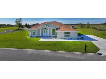 Charming single-Gathering home featuring a well-manicured lawn, neutral stucco, and a concrete driveway at 9594 Se 61St Ter, Belleview, FL 34420