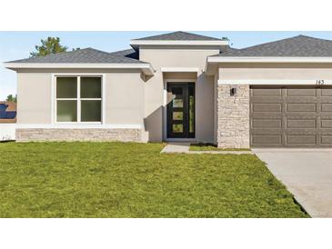 Modern home featuring stone accents, neutral colors, and a well-manicured lawn at 2728 Sw 154Th Pl, Ocala, FL 34473