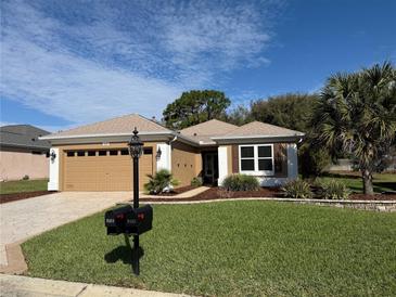 Charming single-story home with a well-manicured lawn and an attached two-car garage at 9369 Se 124Th Loop, Summerfield, FL 34491