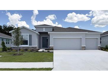 Charming single-story home featuring a two car garage, neutral paint, stone accents and a well manicured lawn at 3071 Canopy Oak Blvd, Wildwood, FL 34785