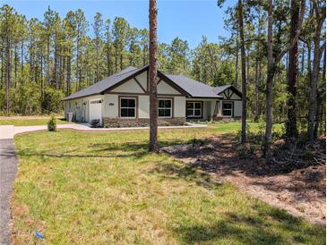 Well-maintained home with lush lawn, stone accents, and a two-car garage at 8303 Sw 127 Ave, Dunnellon, FL 34432