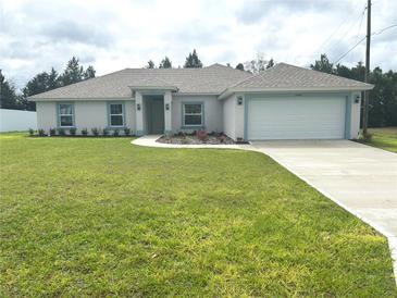 Charming single-story home featuring a well-manicured lawn, two-car garage, and complementary blue trim at 5646 Sw 129Th Place Rd, Ocala, FL 34473