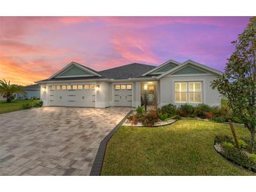 Charming one-story home with a three-car garage, brick paver driveway, and landscaped front yard at 6918 Baysinger Path, The Villages, FL 34762