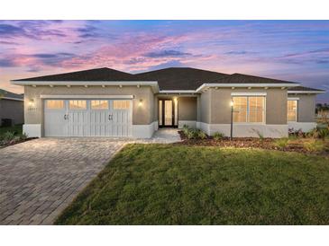 Charming single-story home featuring a paved driveway, two-car garage, and nicely manicured lawn at 10557 Sw 98Th Ln, Ocala, FL 34481
