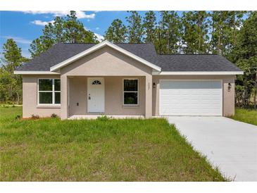 Charming single-story home features a fresh lawn, an attached garage, and a neutral stucco exterior at 127 Sw Alvarez Rd, Dunnellon, FL 34431