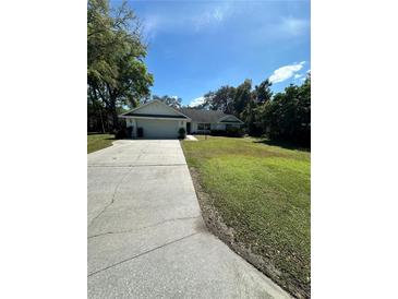 Well-maintained single-story home with a long driveway and lush green lawn at 19726 Sw 95Th St, Dunnellon, FL 34432