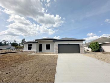 Charming single-story home featuring a two-car garage, stone accents, and a well-maintained lawn at 3085 Sw 131St Place Rd, Ocala, FL 34473