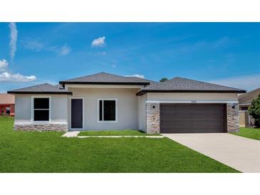 New construction home features stone accents, dark garage door, neutral paint, and green grass at 3085 Sw 131St Place Rd, Ocala, FL 34473