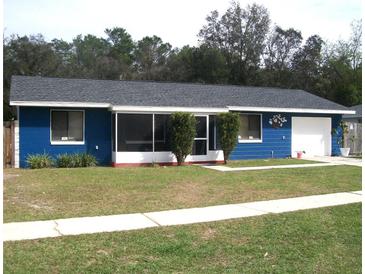 Charming single-story blue home with a well-maintained lawn and walkway at 409 Marion Oaks Dr, Ocala, FL 34473