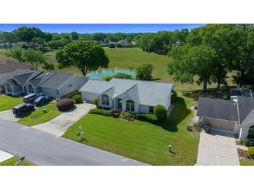 Inviting single-story home with manicured lawn, pond view, and mature trees in a serene community at 8832 Sw 108Th St, Ocala, FL 34481