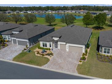 Beautiful single-story home showcasing a large driveway and a tranquil water view in a desirable neighborhood at 8825 Sw 57Th Place Rd, Ocala, FL 34481