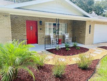 Charming single-story brick home featuring a bright red front door and landscaped front yard at 10076 Se 139Th Pl, Summerfield, FL 34491