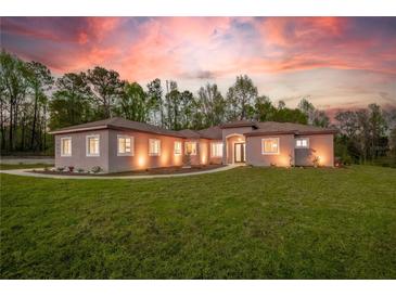 Charming single-story home with well-manicured lawn and beautiful landscape under a colorful sunset sky at 4869 Nw 101St Street Rd, Ocala, FL 34482