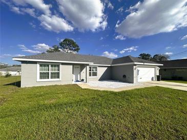 A well-maintained single-story home with gray stucco, a two-car garage, and a front yard at 15055 Se 93Rd Ct, Summerfield, FL 34491