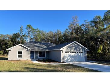 Charming single-story home featuring a gray exterior, a well-manicured lawn, and an attached two-car garage at 114 Bay Dr, Ocklawaha, FL 32179