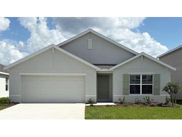 Charming single-story home with a two-car garage, manicured lawn, and light green front door at 4770 Sw 88Th Ln, Ocala, FL 34476