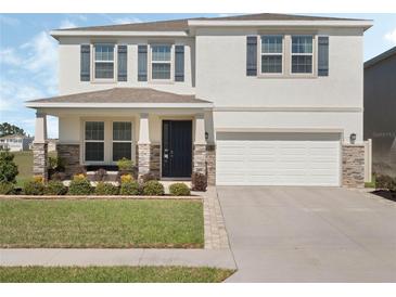 Charming two-story home featuring a manicured lawn, stone accents, and a welcoming front porch at 5021 Sw 88Th St, Ocala, FL 34476