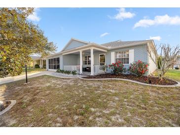 Charming single-story home boasts a screened porch, manicured lawn and vibrant red flower bushes at 9770 Sw 97Th Pl, Ocala, FL 34481